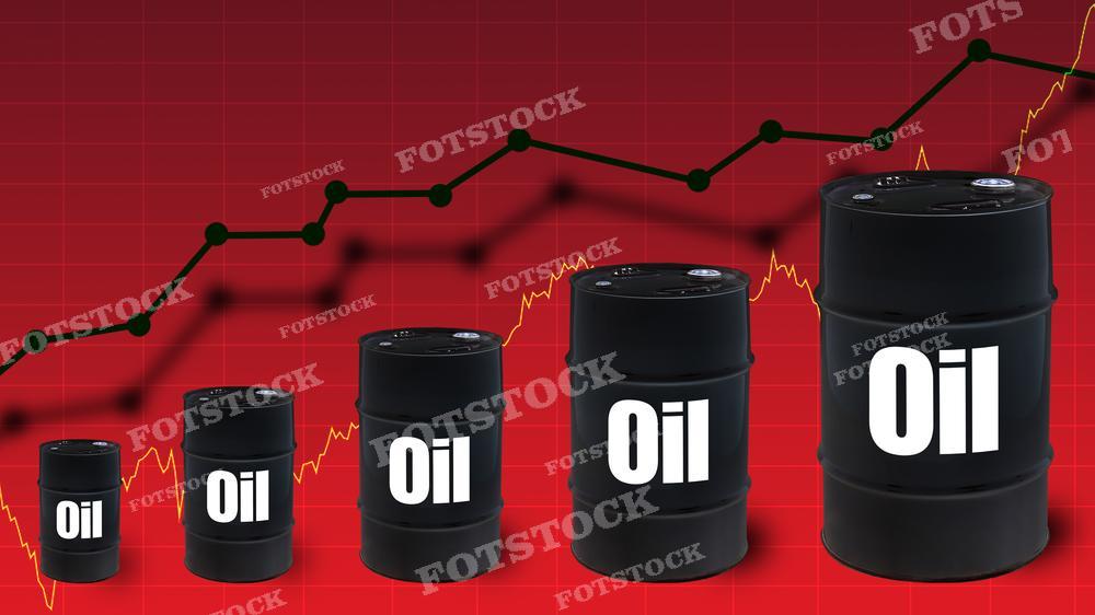 На изображении видны черные нефтяные бочки с белыми надписями "Oil", которые увеличиваются в размере слева направо, создавая эффект роста. На заднем плане изображен график цен на нефть, с линией тренда, которая показывает спад и последующий рост цен на нефть. Фон в красном цвете может символизировать рыночные колебания или нестабильность. Такое фото может использоваться для иллюстрации материалов о динамике цен на нефть, её влиянии на экономику или в бизнес-презентациях, связанных с энергетическим сектором.
